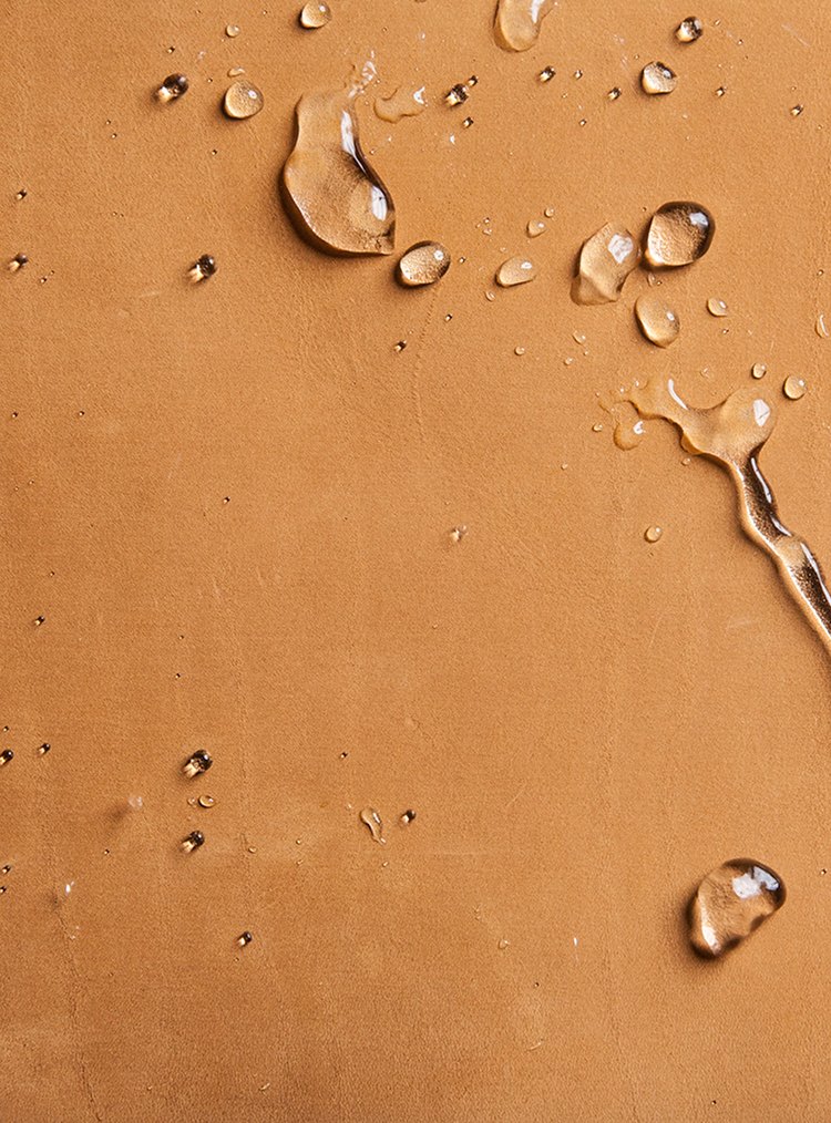 A close up images of textured waterproof leather with beads of water on it.