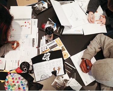 Kids sitting at a table designing boots.