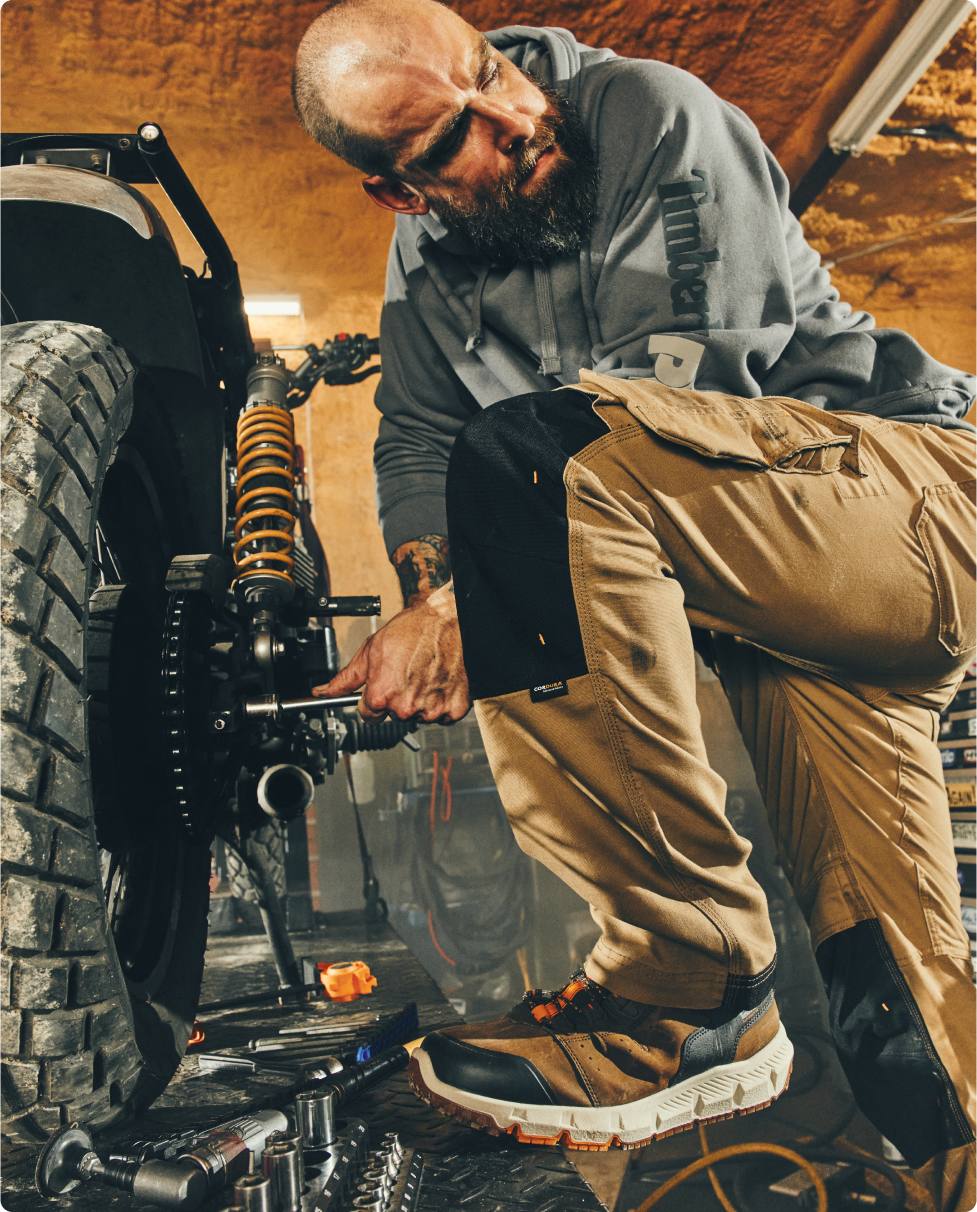 A man working on a motorcycle wearing Timberland® PRO boots.