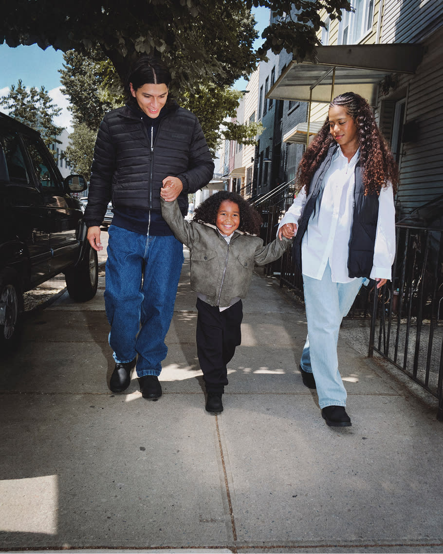 a man and woman holding hands with a child wearing black boots
