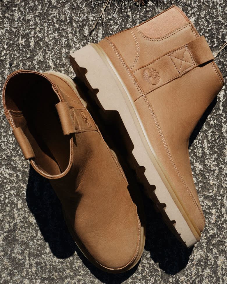 brown chelsea boots on concrete with one lying on its side