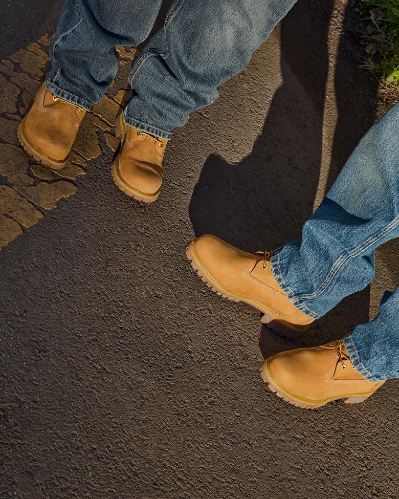 two pairs of legs in yellow timberland boots and jeans