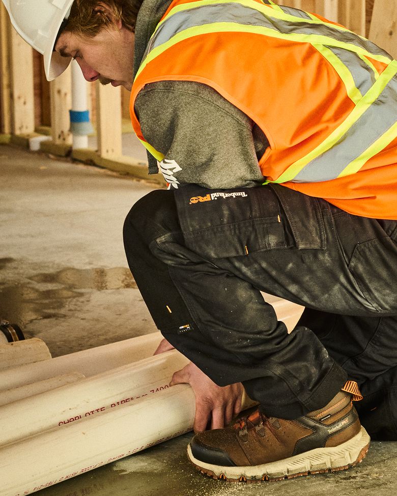 construction worker bending down to tie the laces on a timberland work boots