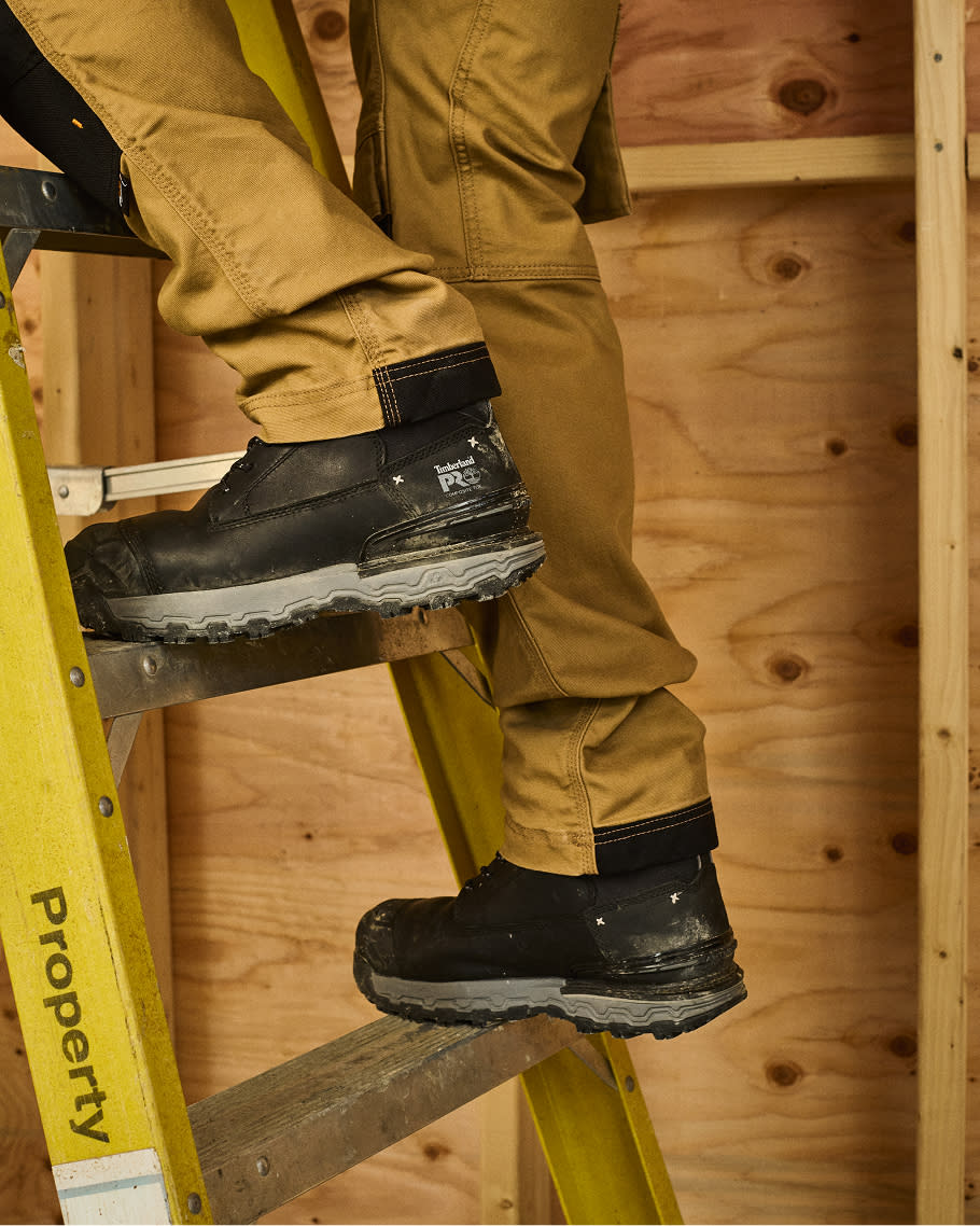 worker climbing on a ladder in brown pants and construction work boots
