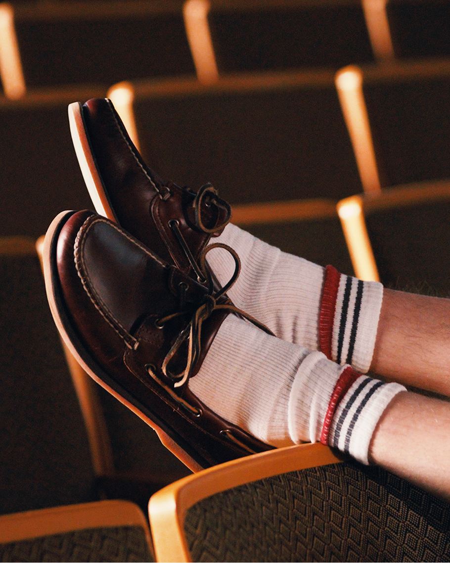 a pair of feet wearing black loafers and white socks resting on a wooden chair