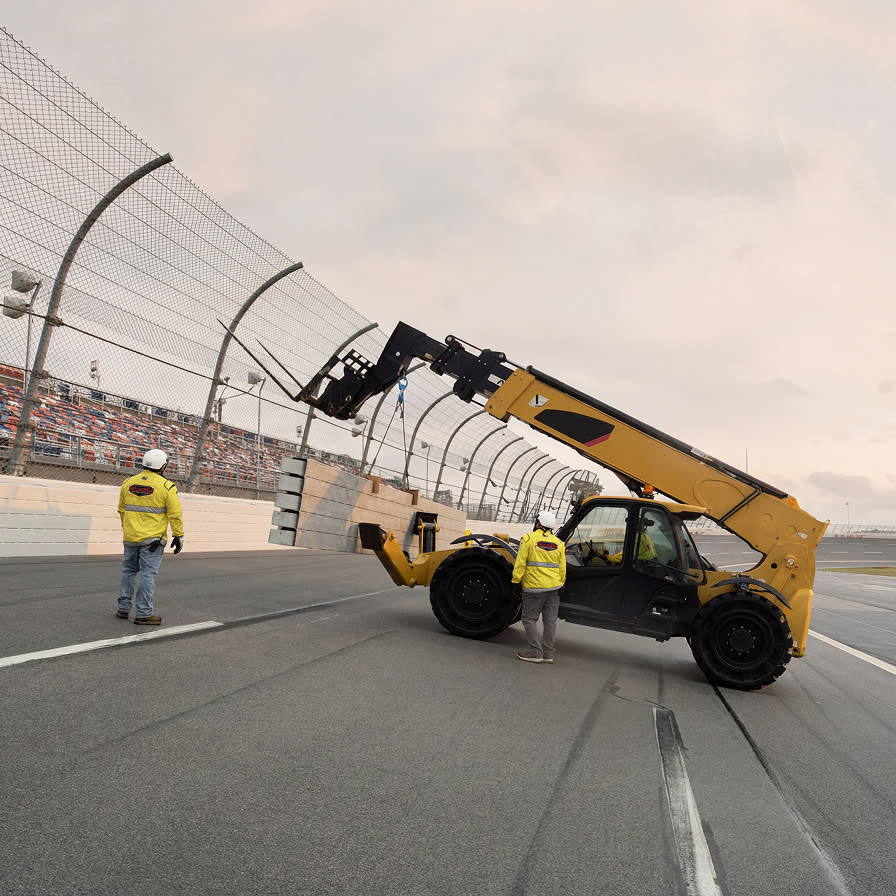A few Nascar crew members working to repair a fence on the track.