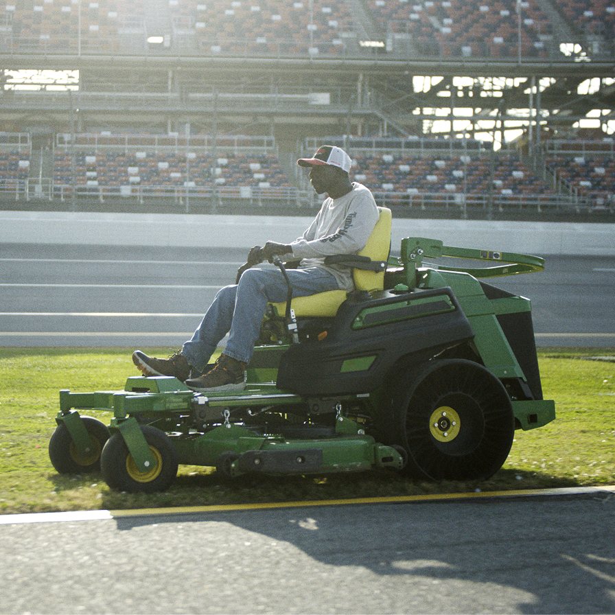 A person riding a lawn mower on a sunny day.