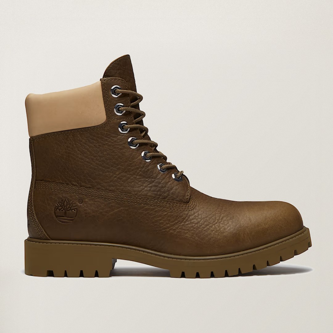 Timberland Premium 6-Inch boot in dark brown leather with a tan leather collar, brass lace eyelets, embossed tree logo on the heel, and a dark tan outsole, shown in side profile.