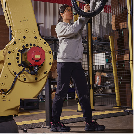 A women working on heavy machinery in a factory setting.