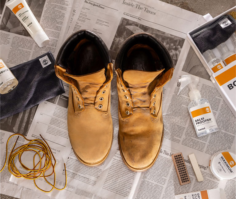 Picture of a pair of boots being cleaned with various Timberland product care items.