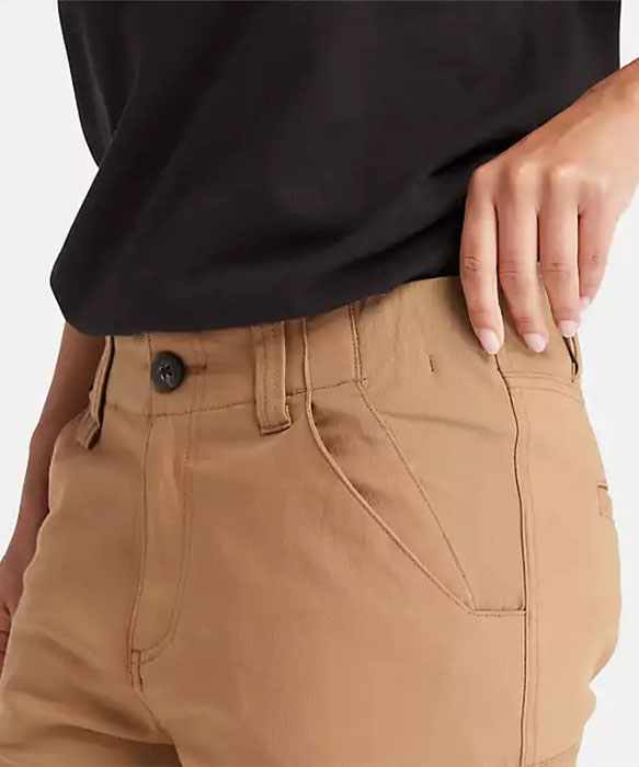 Image of a section of waistband on a brown work pant being worn by someone whose hand is pulling up the band just a bit to show the stretch.