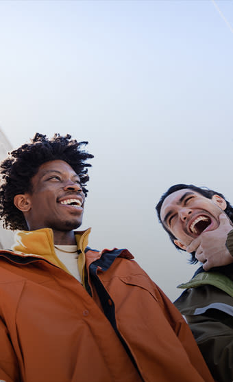 Two people smiling against a blue sky