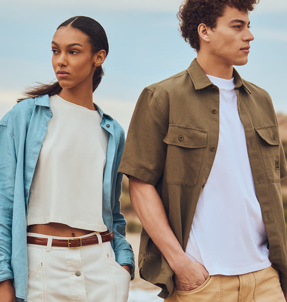 A man and women standing on a rocky shore.