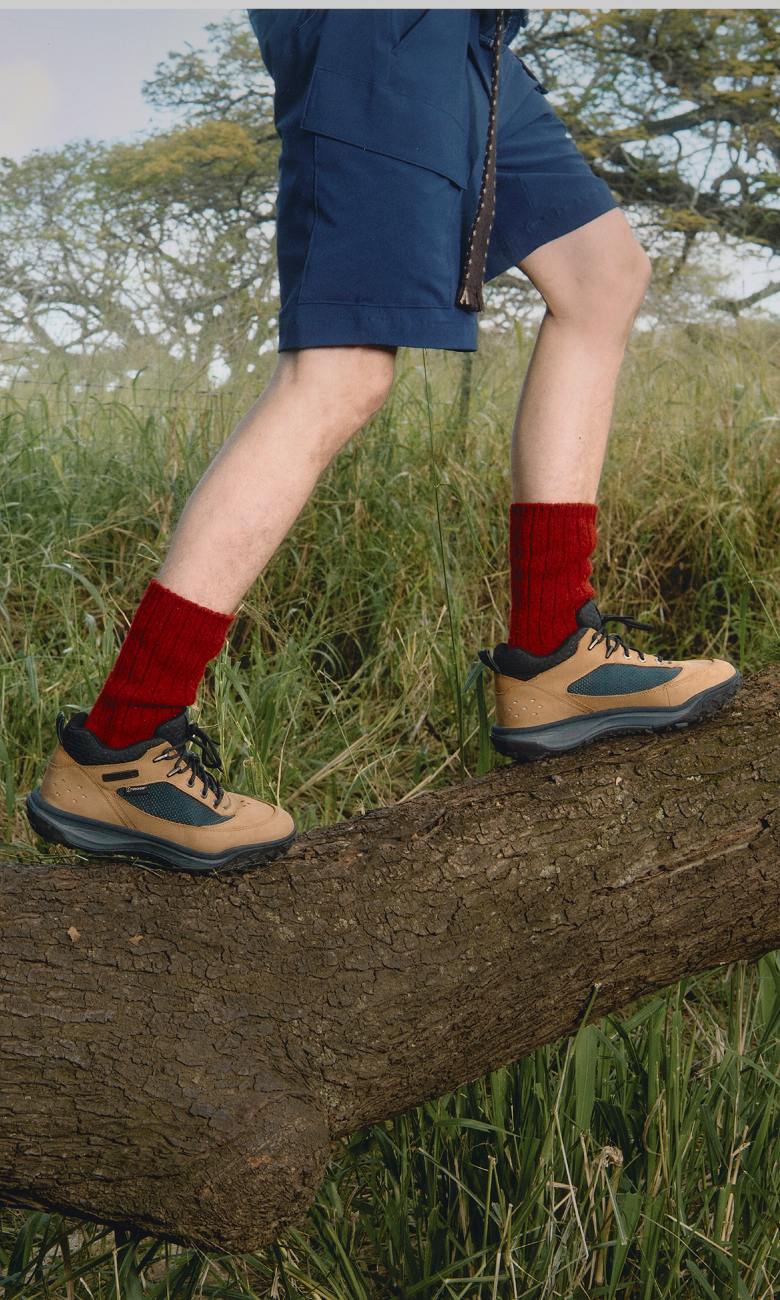A pair of feet in red socks and boots stepping on a log.