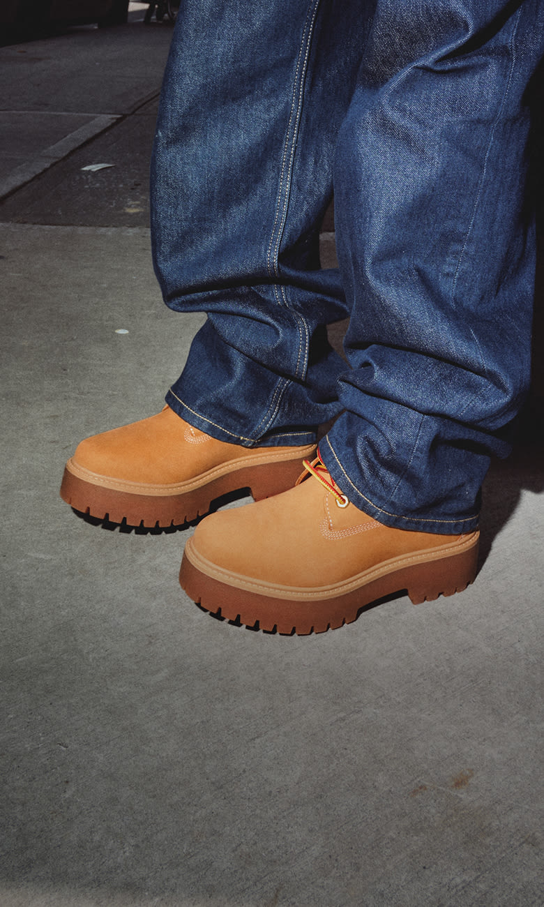 a pair of feet wearing timberland shoes and jeans
