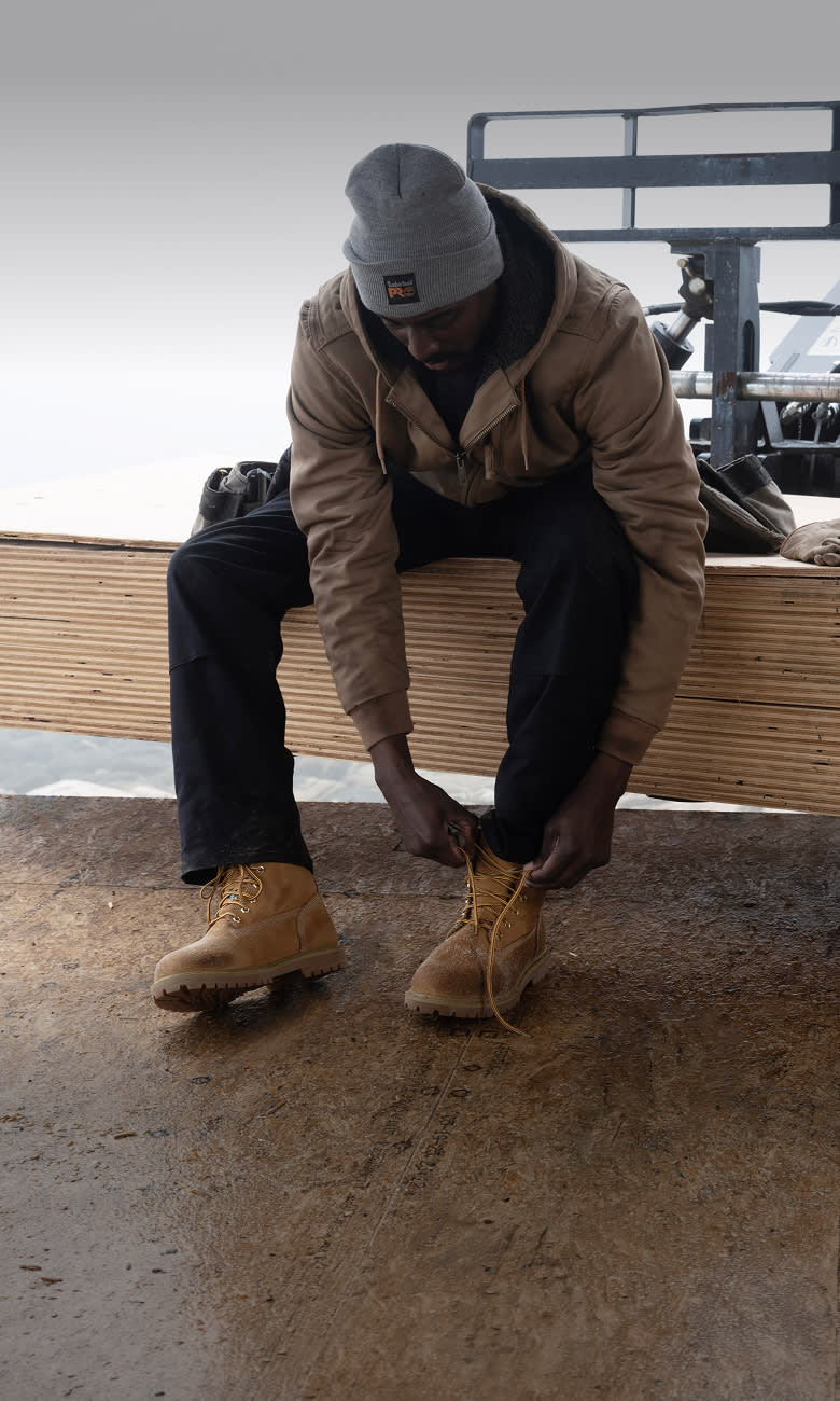 construction worker tying the laces on his steel toe work boots