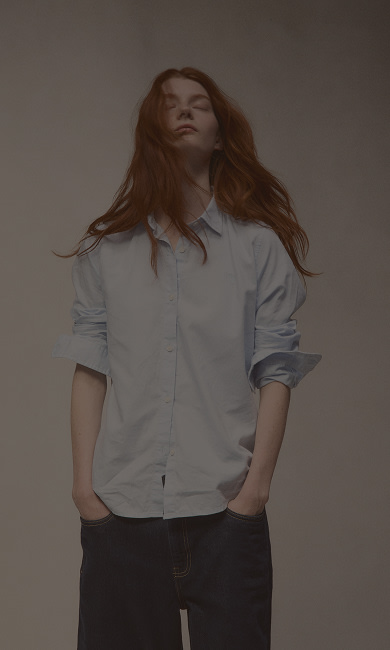 woman with red hair and minimalist blue button up shirt