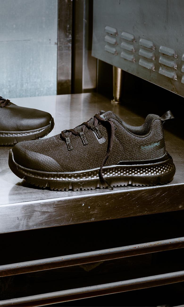 a pair of black sneakers on a slippery metal surface covered in water droplets